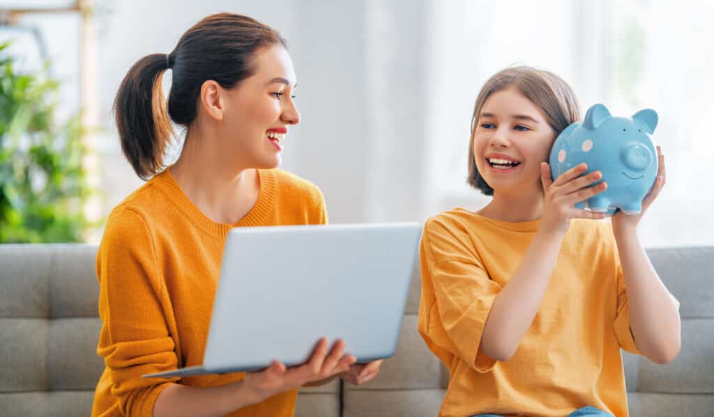 virtual assistant for doctors Mother and daughter are holding piggy bank and laptop sitting at home