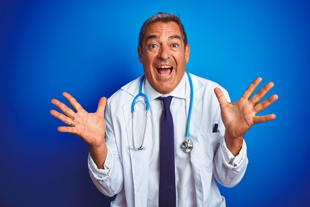 Handsome middle age doctor man wearing stethoscope over isolated blue background