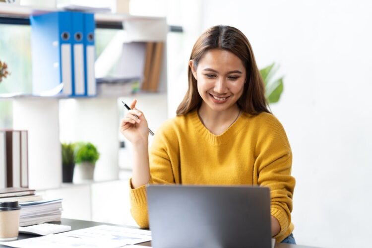 transcription a girl infront of her laptop smiling