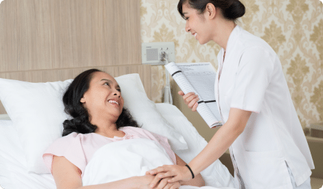 nurse talking to her patient while lying in the hospital bed