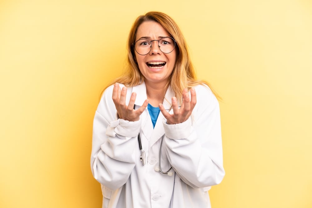 pretty blonde young woman looking desperate, frustrated and stressed. physician or doctor student concept