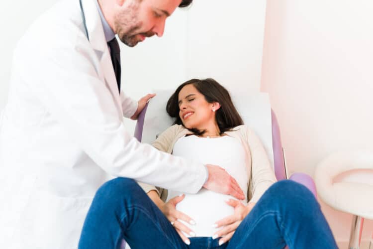 Expectant mother with pain and cramps complaining about her symptoms with a male doctor