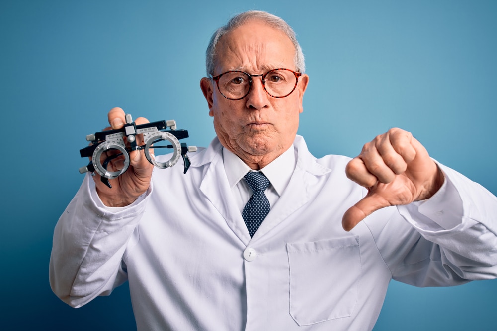 senior doctor holding a optometrist eyeglasses with a thumbs down hand