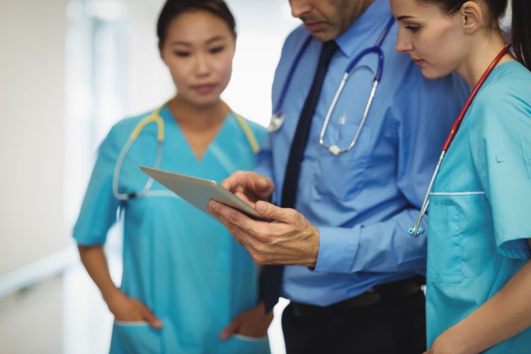 nurses and doctor discussing over digital table