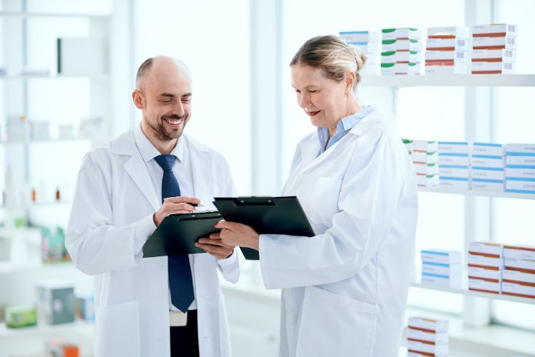 pharmacists discuss something standing near the shelf