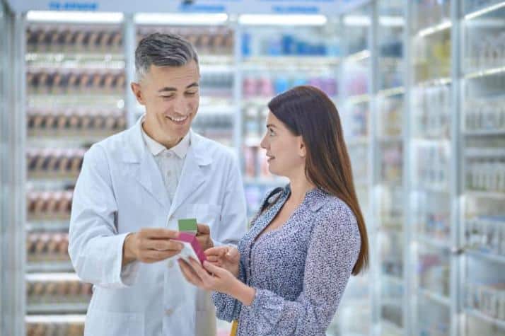 prior authorization pharmacist handing over medication to a patient with a smile in a pharmacy