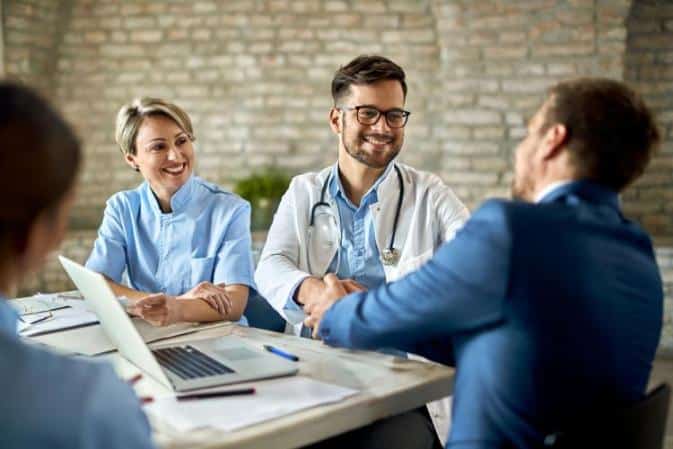 prior authorization specialist doctors around the table shaking hand with patient