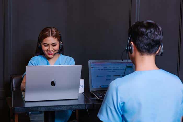 female wearing scrub with laptop