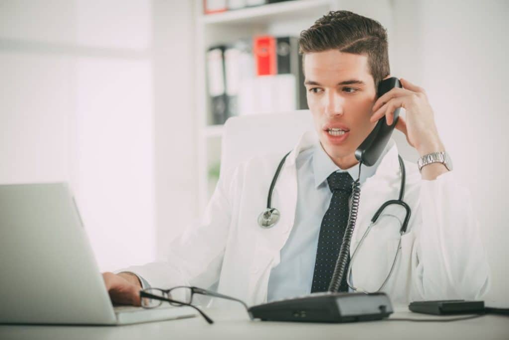 emergence of virtual medical receptionists doctor taking a pone call while using laptop
