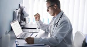 practice management with virtual medical receptionists, doctor using laptop