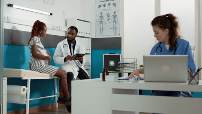 prior authorization specialist remote, a doctor talking to a pregnant patient, woman using laptop