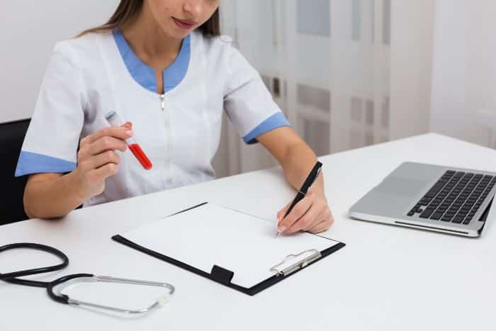 prior authorization unveiled medical form Female doctor hand writing a report and holding a blood sample