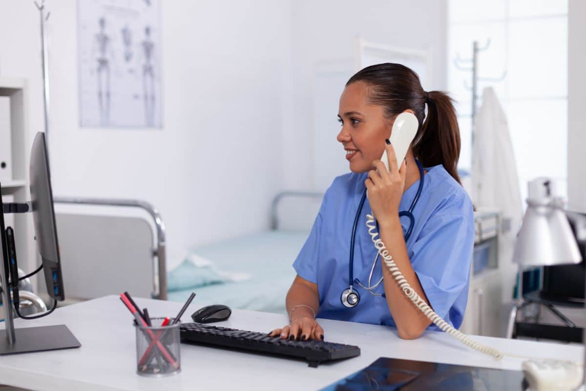 virtual medical receptionist healthcare processes, doctor using a telephone while using the computer