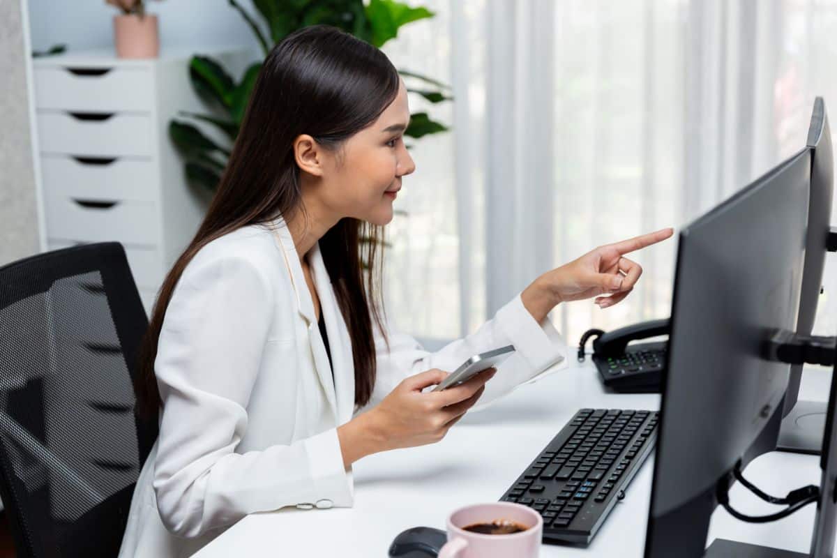 impact of virtual medical receptionists female holding a phone and pointing on the monitor