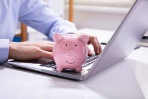 saving money with virtual medical receptionist doctor using laptop with a piggy bank