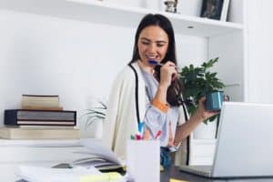 dental receptionist in front of laptop while holding cup and pen