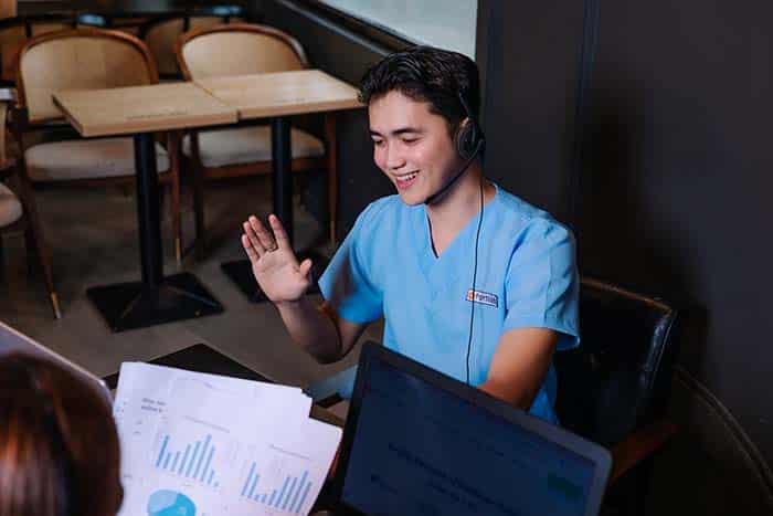 male wearing blue scrub waving