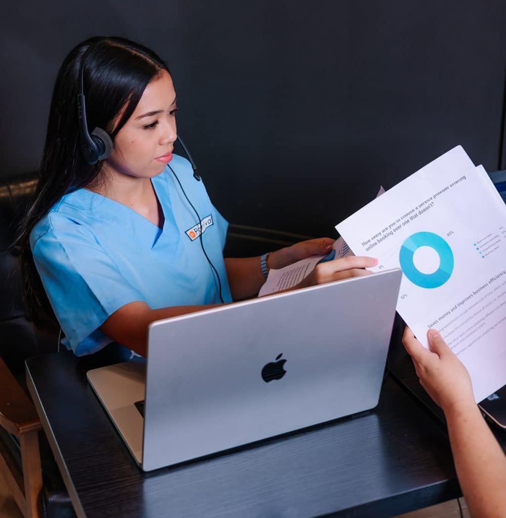 ER Scribe reviewing patient documentation on a laptop while discussing medical charts with a colleague in a healthcare setting