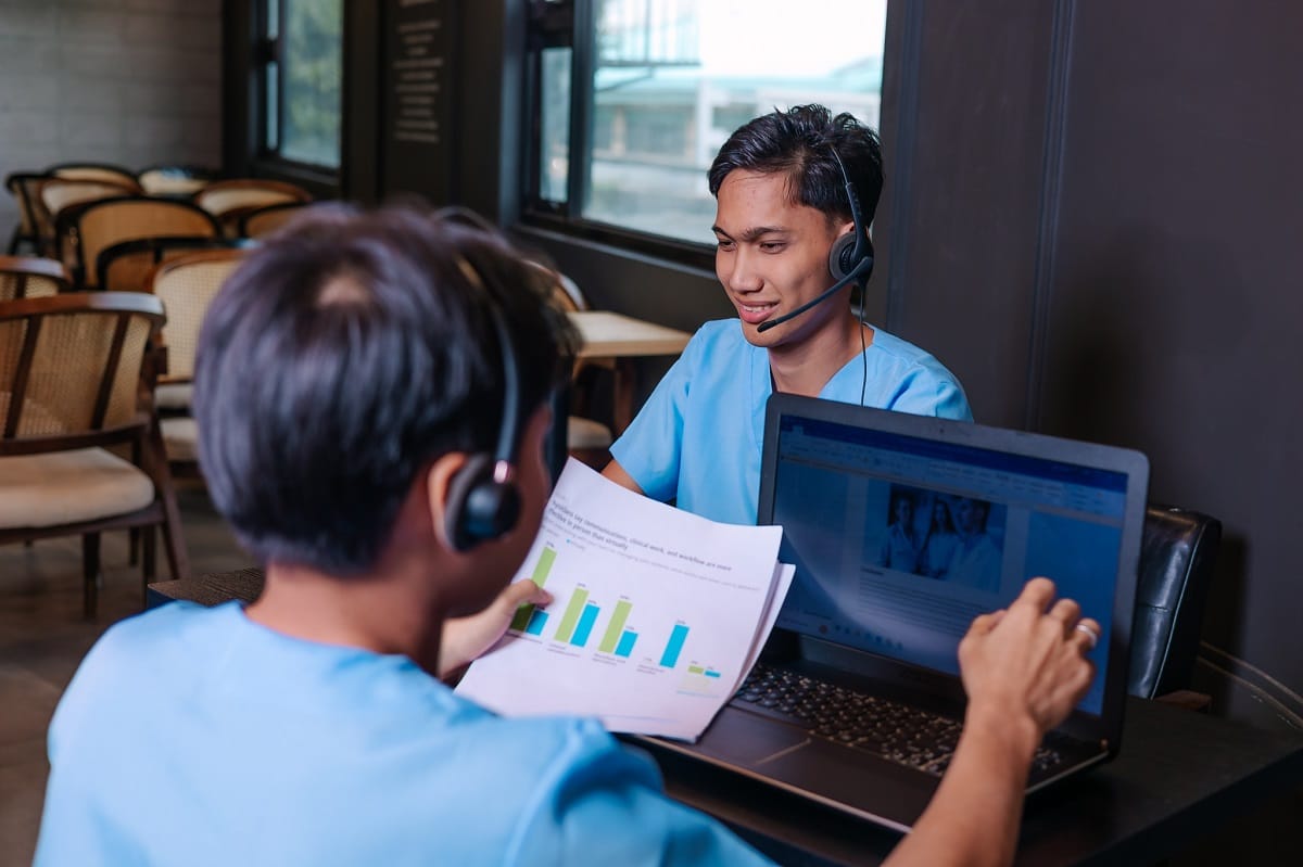 Otolaryngology medical billing services with two medical billing professionals with headsets review charts and a laptop.