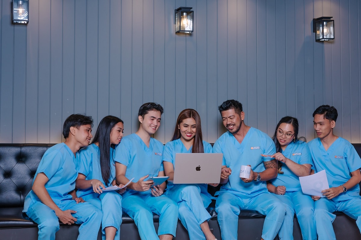 medical documentation examples with seven young healthcare professionals in light blue scrubs sit on a sofa