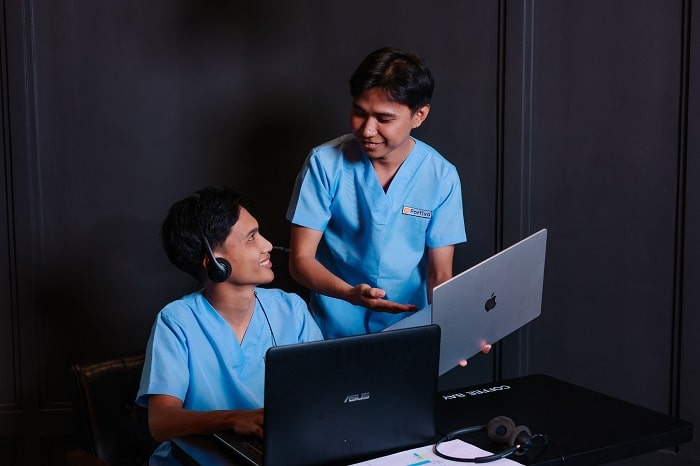 two people in light blue scrubs and headsets