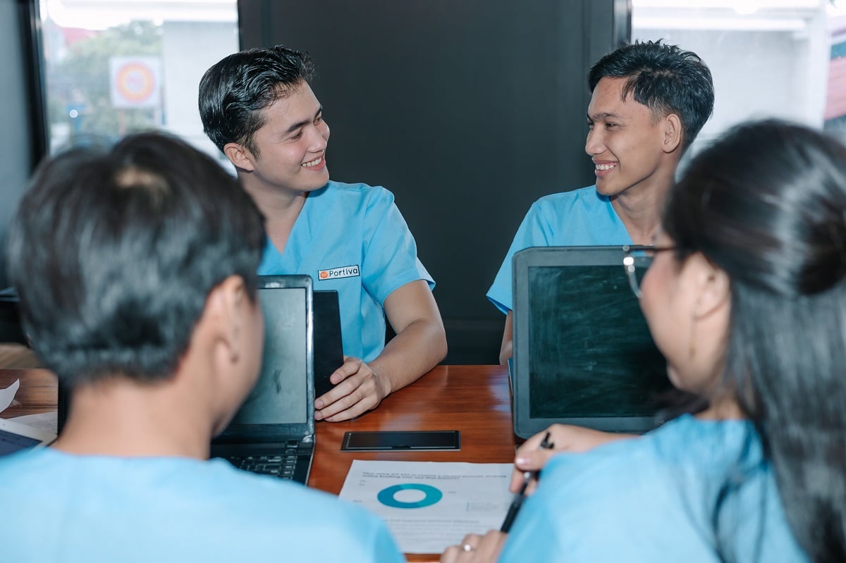 what is pos 11 in medical billing with four medical professionals in blue scrubs collaborating around a wooden table.