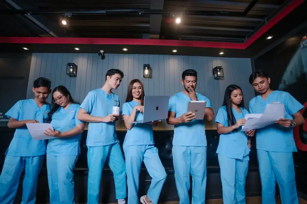 Patient follow up virtual assistant team reviewing patient outreach tasks, appointment follow-ups, and communication workflows while using digital devices