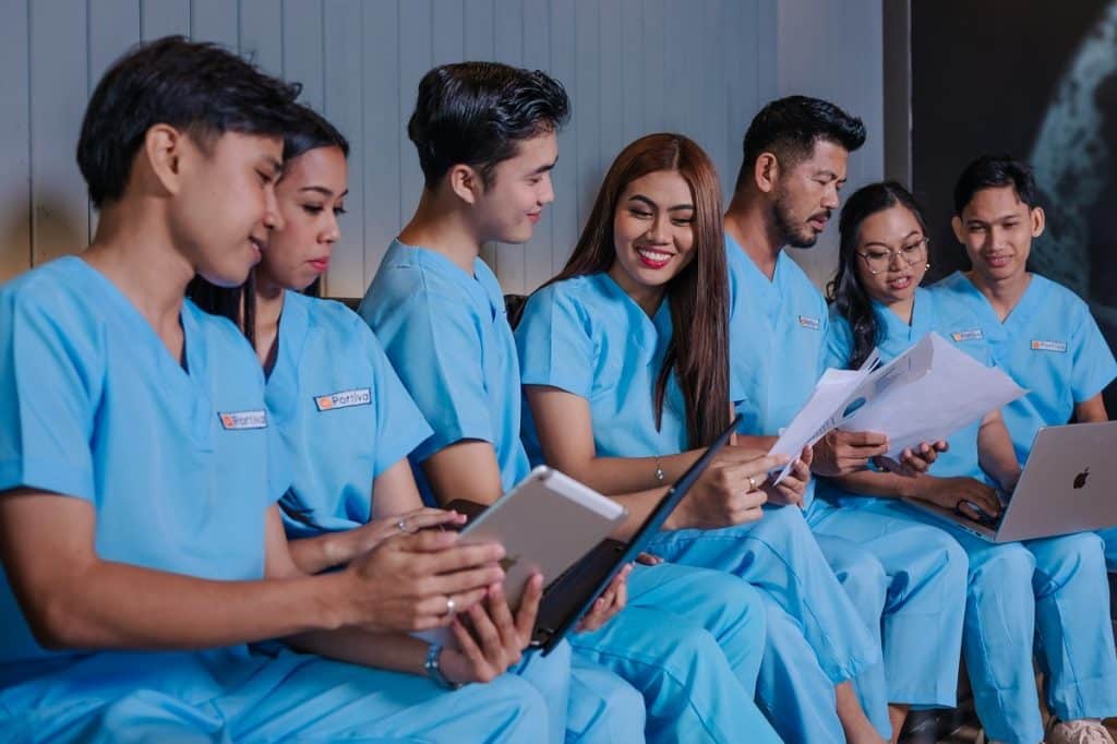 front desk call routing patient experience healthcare administrative team reviewing patient documents and coordinating workflows using tablets and laptops in a clinical setting