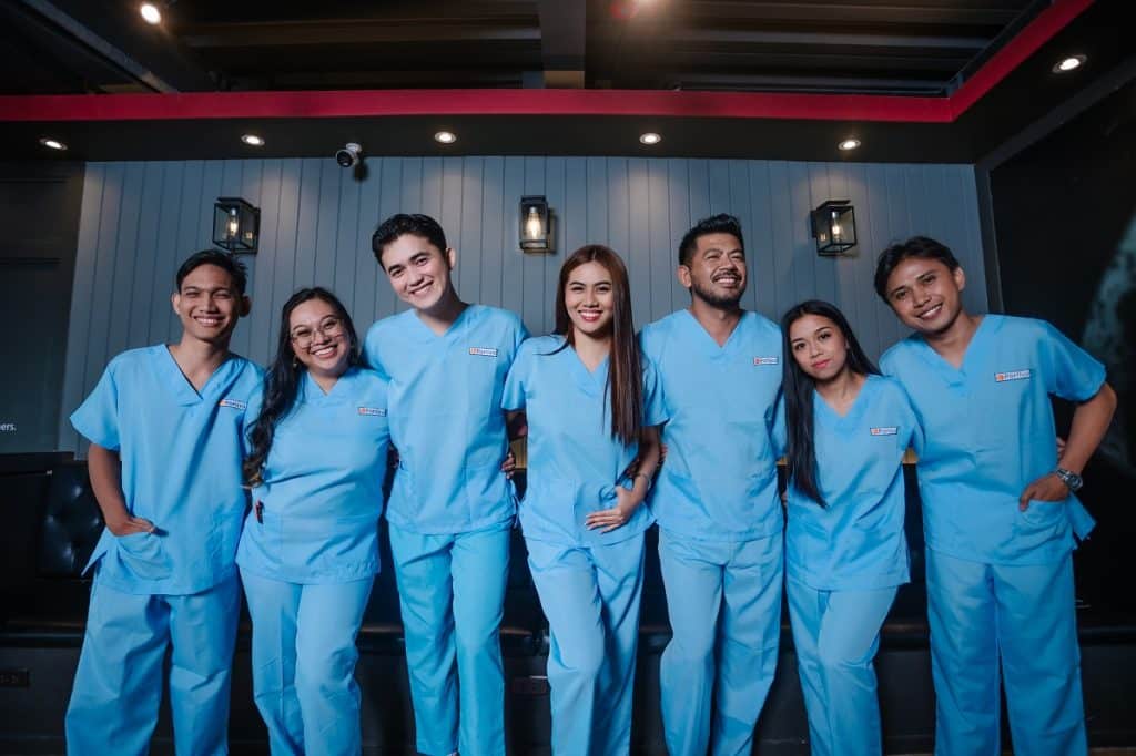 healthcare contact center conversion leaks team members in blue medical scrubs smiling together in a modern office setting, showcasing a friendly and professional healthcare support environment