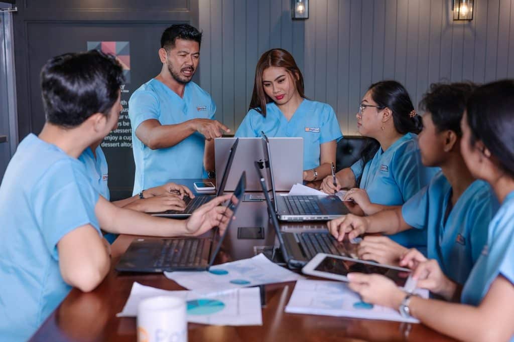 patient referral VIP segment follow up workflow team collaborating on laptops and documents during a strategic healthcare coordination meeting