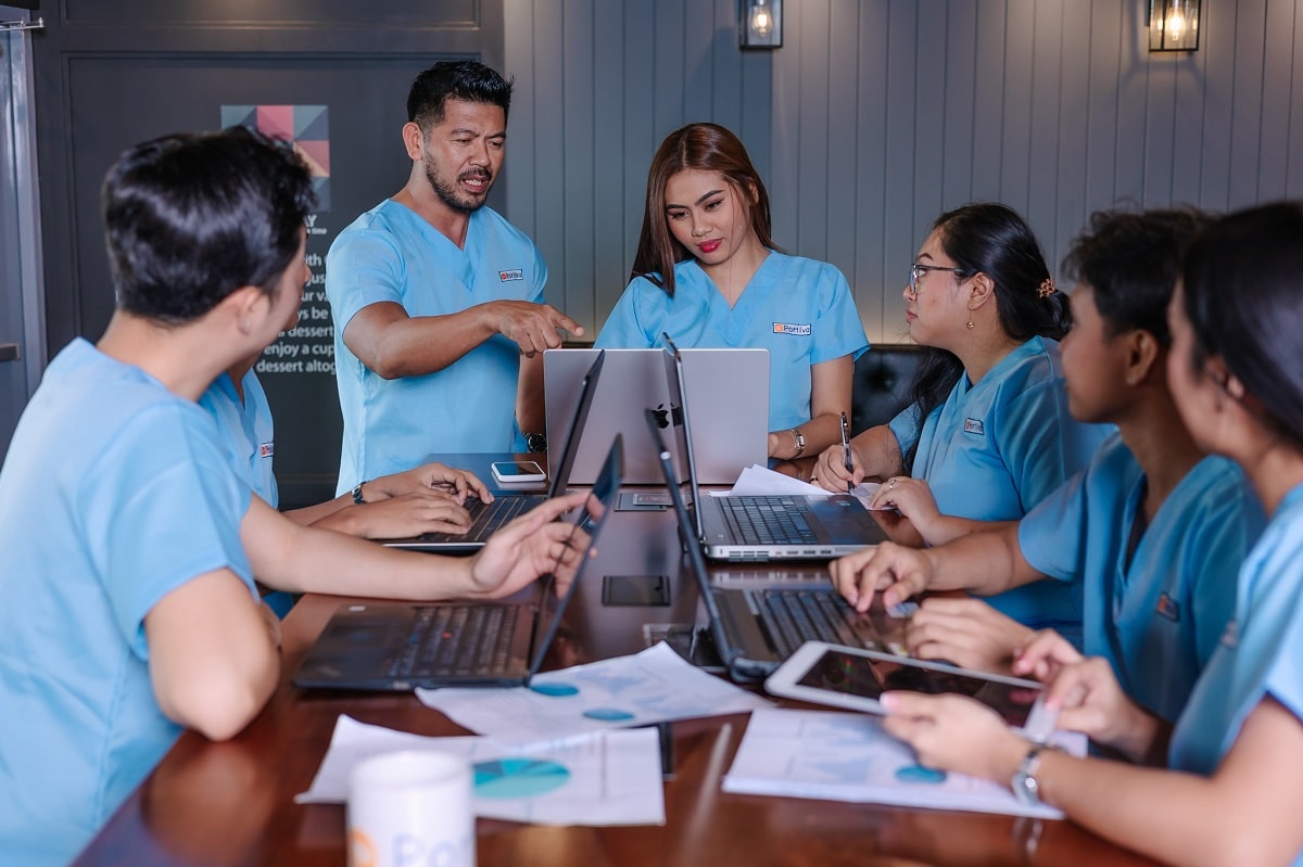patient referral VIP segment follow up workflow team collaborating on laptops and documents during a strategic healthcare coordination meeting