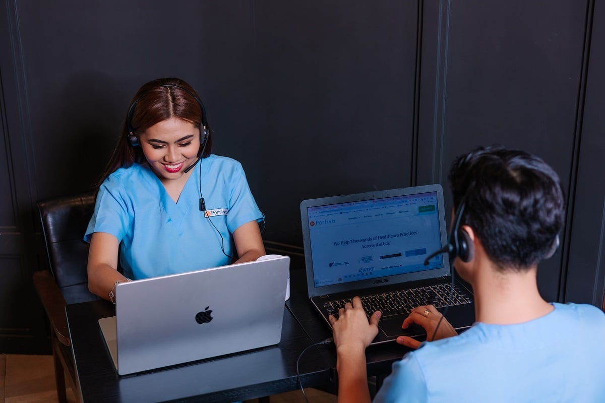 Prior authorization support workflow specialist wearing a headset assists a colleague during a virtual healthcare coordination session